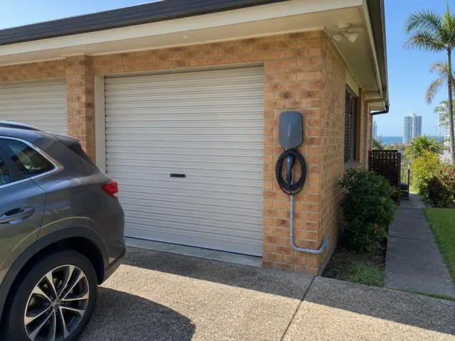 Wall-mounted EV charger beside a garage on a brick home exterior in Coolangatta