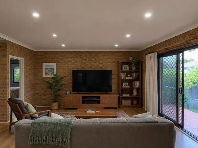Living room with recessed LED downlights in a brick-walled home interior in Tugun